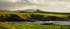 A distant building surrounded by fields and coastal cliffs
